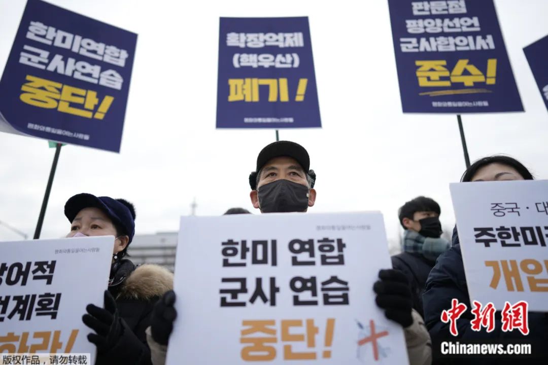 当地时间2023年1月31日，韩国首尔，抗议者在国防部外的集会上举着“停止美韩联合军事演习”的标语。
